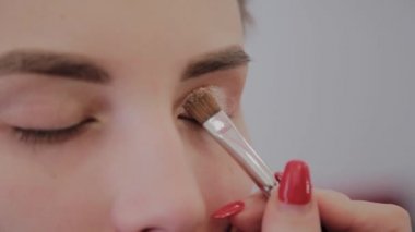 Makyaj sanatçısı güzel bir genç kıza profesyonel makyaj uygular. Makyaj yeni konsept.