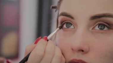 Makyaj sanatçısı güzel bir genç kıza profesyonel makyaj uygular. Makyaj yeni konsept.