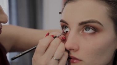 Makyaj sanatçısı güzel bir genç kıza profesyonel makyaj uygular. Makyaj yeni konsept.