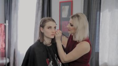 Makyaj sanatçısı güzel bir genç kıza profesyonel makyaj uygular. Makyaj yeni konsept.