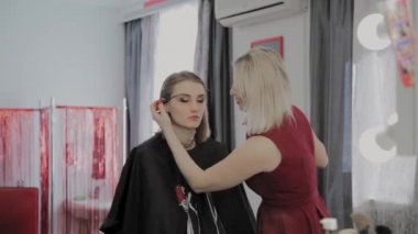 Makyaj sanatçısı güzel bir genç kıza profesyonel makyaj uygular. Makyaj yeni konsept.