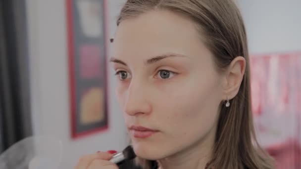 Makeup artist applicerar professionell makeup till en vacker ung flicka. Nytt koncept i makeup. — Stockvideo