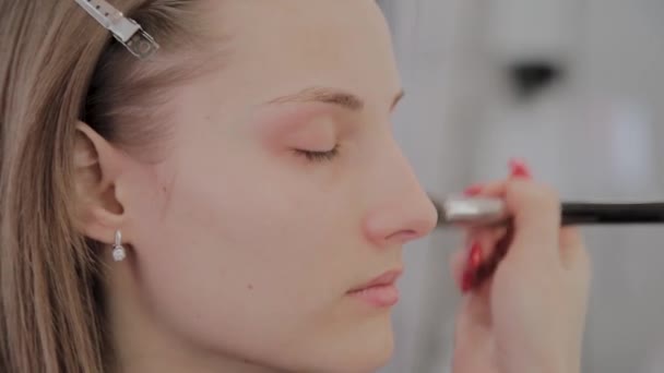 Makeup artist applicerar professionell makeup till en vacker ung flicka. Nytt koncept i makeup. — Stockvideo