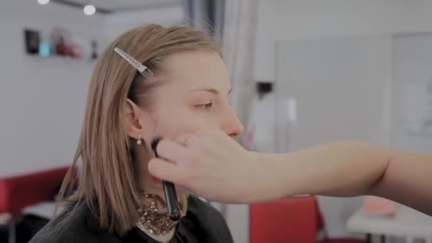 Makeup artist applicerar professionell makeup till en vacker ung flicka. Nytt koncept i makeup. — Stockvideo