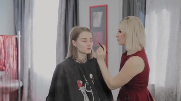 Makeup artist applicerar professionell makeup till en vacker ung flicka. Nytt koncept i makeup. — Stockvideo