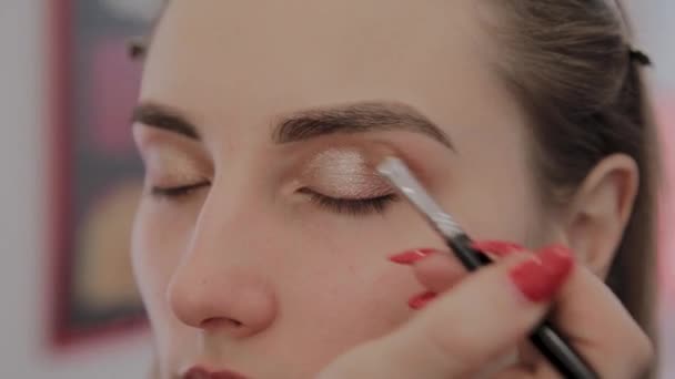 Makeup artist applicerar professionell makeup till en vacker ung flicka. Nytt koncept i makeup. — Stockvideo