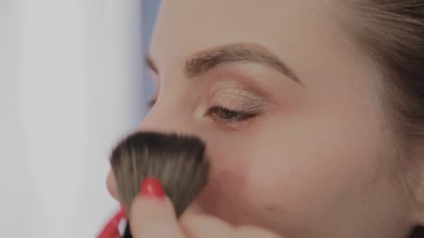Maquiagem artista aplica maquiagem profissional para uma bela jovem. Novo conceito em maquiagem . — Vídeo de Stock