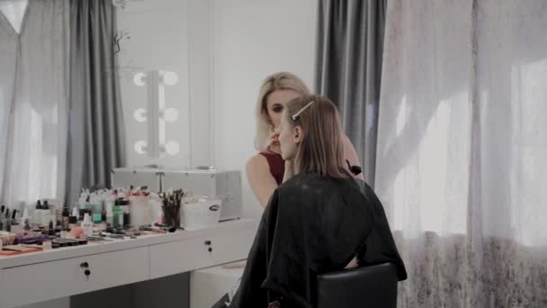 Makeup artist applies professional makeup to a beautiful young girl. New concept in makeup. — Stock Video