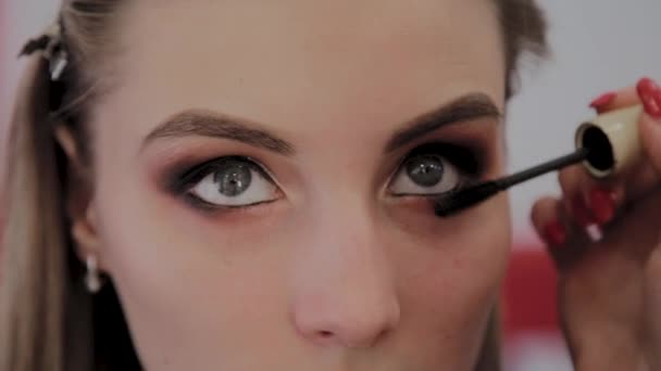 Maquillaje artista aplica maquillaje profesional a una hermosa joven. Nuevo concepto en maquillaje . — Vídeo de stock