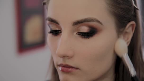 Makeup artist applicerar professionell makeup till en vacker ung flicka. Nytt koncept i makeup. — Stockvideo