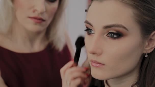 Makeup artist applica il trucco professionale a una bella ragazza. Nuovo concetto di trucco . — Video Stock