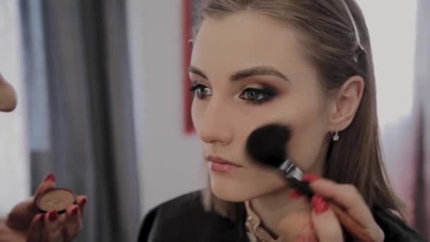 Makeup artist applies professional makeup to a beautiful young girl. New concept in makeup. — Stock Video