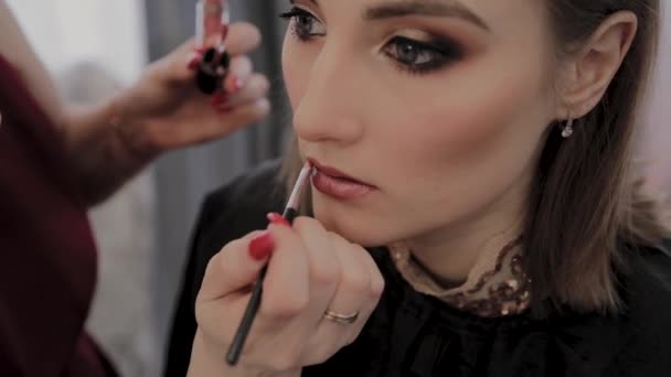 Maquilleuse applique un maquillage professionnel à une belle jeune fille. Nouveau concept dans le maquillage . — Video
