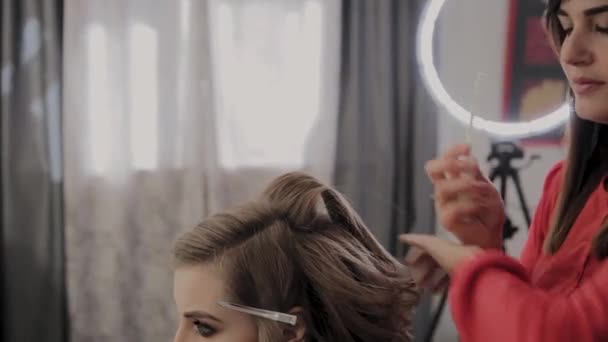 Профессиональный парикмахер делает девушкам прическу для фотосессии . — стоковое видео