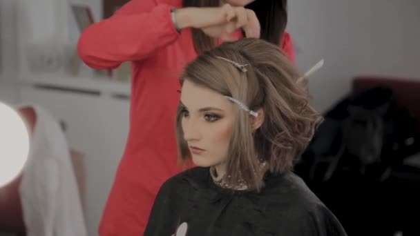 Cabeleireiro profissional faz um penteado meninas para uma sessão de fotos . — Vídeo de Stock