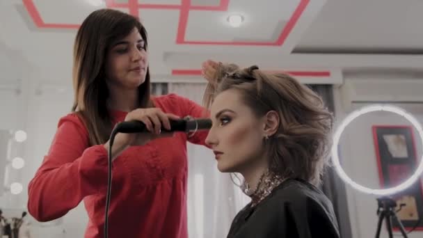 Professional hairdresser does a girls hairstyle for a photo shoot. — Stock Video