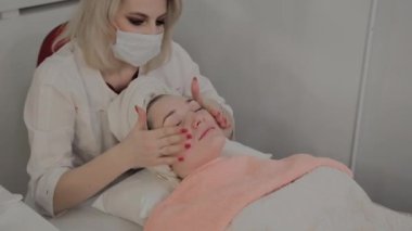 Profesyonel bir Kozmetolog bir maske uygulamadan önce bir yüz Masaj prosedürü yapar. Kozmetolojide yeni konsept.