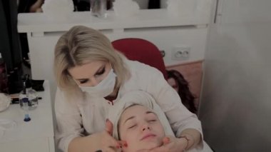 Profesyonel bir Kozmetolog bir maske uygulamadan önce bir yüz Masaj prosedürü yapar. Kozmetolojide yeni konsept.