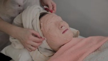Profesyonel Güzellik genç bir kızın yüzüne maske kaldırır. Kozmetolojide yeni konsept.