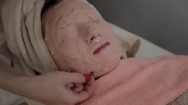 Profesyonel Güzellik genç bir kızın yüzüne maske kaldırır. Kozmetolojide yeni konsept.