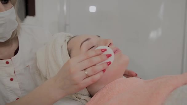 Profesjonalny kosmetolog pociera twarz dziewcząt specjalnymi chusteczki nawilżające. Nowa koncepcja w kosmetologii. — Wideo stockowe
