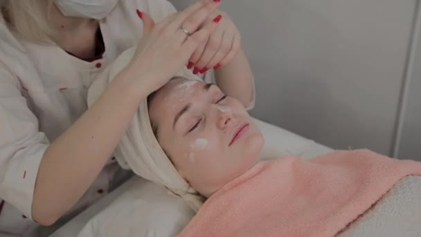 Un cosmetólogo profesional hace un procedimiento de masaje facial antes de aplicar una máscara. Nuevo concepto en cosmetología . — Vídeo de stock