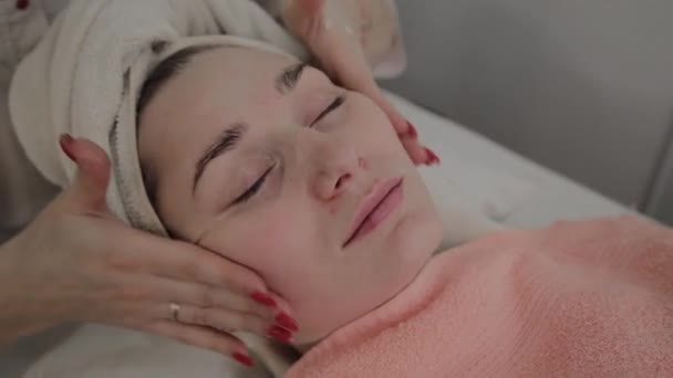 Een professionele schoonheidsspecialist doet een gezicht massage procedure voor het aanbrengen van een masker. Nieuw concept in cosmetica. — Stockvideo