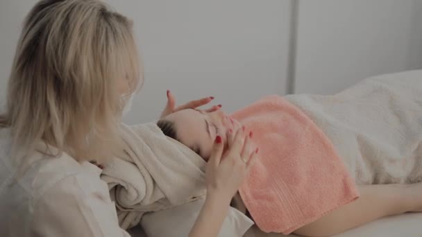 Een professionele schoonheidsspecialist doet een gezicht massage procedure voor het aanbrengen van een masker. Nieuw concept in cosmetica. — Stockvideo