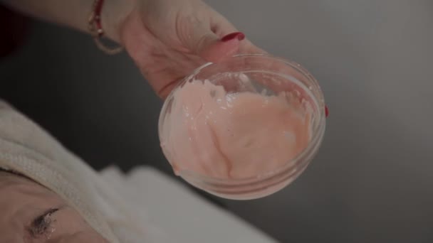 Trägt ein professioneller Kosmetiker einem jungen Mädchen mit einem Pinsel eine Gesichtsmaske auf. Neues Konzept in der Kosmetologie. — Stockvideo