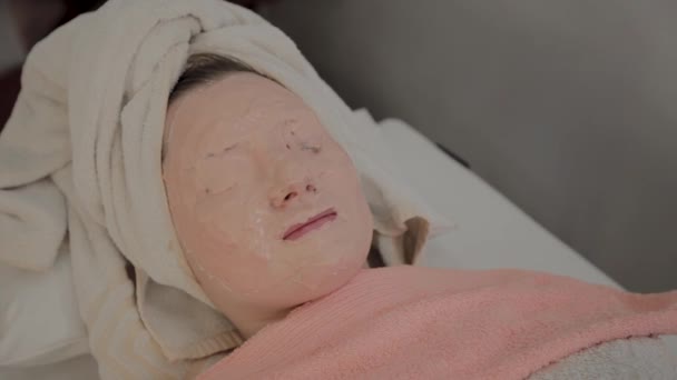 Verjüngende Maske auf dem Gesicht eines jungen Mädchens in einem Schönheitssalon. — Stockvideo
