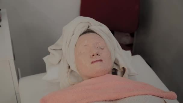 Föryngrande mask på ansiktet av en ung flicka i en skönhets salong. — Stockvideo