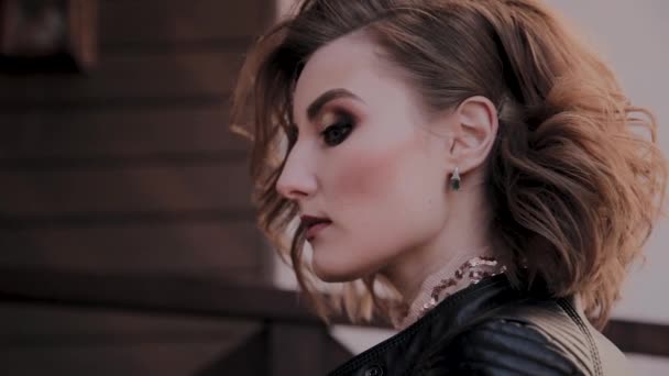 Retrato de una joven modelo con hermoso cabello y maquillaje en una escalera de madera . — Vídeos de Stock