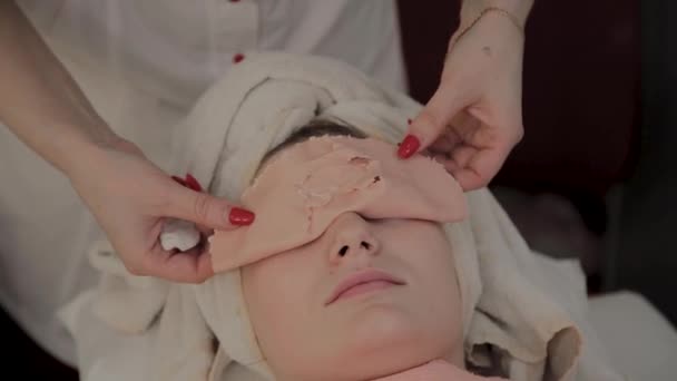 Профессиональный косметолог снимает маску с лица молодой девушки. Новая концепция в косметологии . — стоковое видео