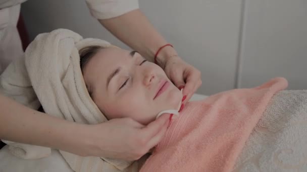 Een professionele schoonheidsspecialist wrijft de meisjes gezicht met speciale hydraterende doekjes. Nieuw concept in cosmetica. — Stockvideo