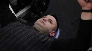 Neşeli şişman adam spor salonunda yanlış Bench Press gerçekleştirir.