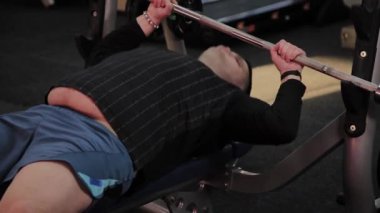 Neşeli şişman adam spor salonunda yanlış Bench Press gerçekleştirir.