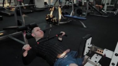 Neşeli şişman adam spor salonunda yanlış bir egzersiz yapar. Fitness kulübünde ilk kez.