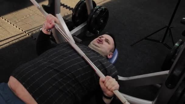 Χαρούμενος χοντρός άνθρωπος εκτελεί το λάθος πρέσα πάγκο στο γυμναστήριο. — Αρχείο Βίντεο