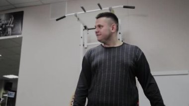 Neşeli şişman adam spor salonunda yanlış bir egzersiz yapar. Fitness kulübünde ilk kez.