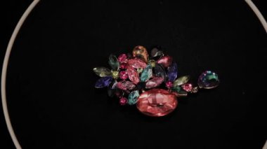 Siyah dönen stand üzerinde renkli broş. Prim Mücevherat.