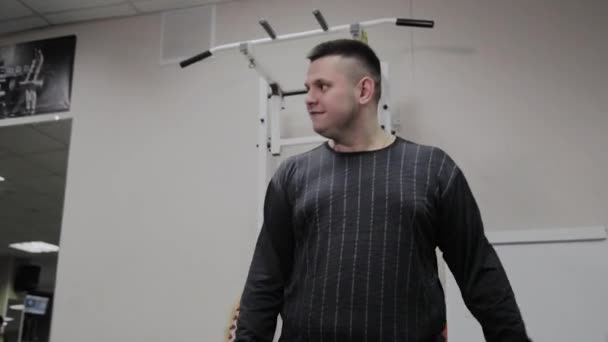 쾌활 한 뚱뚱한 남자는 체육관에서 잘못 된 운동을 수행 합니다. 피트 니스 클럽에서 처음으로. — 비디오