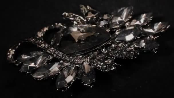 Πόρπη με πέτρες σε μια μαύρη περιστρεφόμενη βάση. Πολυτελή κοσμήματα. Μακροεντολή. — Αρχείο Βίντεο