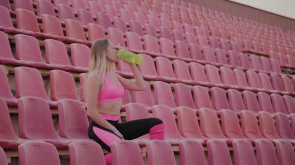 Dívka pije vodu po tréninku na stadionu. — Stock video