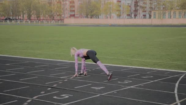 Dívka se zahřeje před tréninkem na stadionu. — Stock video