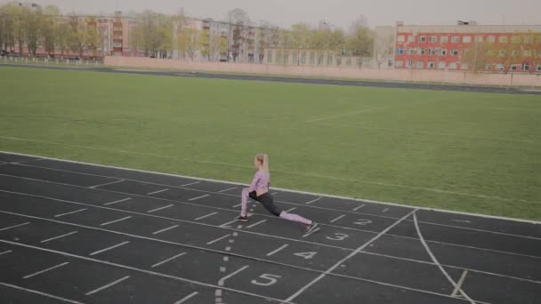 Девушка делает разминку перед тренировкой на стадионе . — стоковое видео
