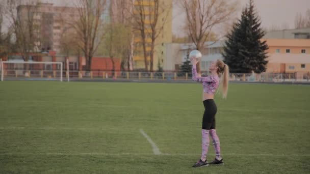 Молодая красивая девушка играет с мячом на стадионе . — стоковое видео