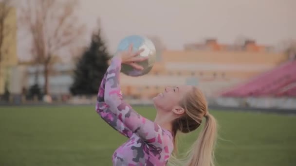 Jong mooi meisje spelen met een bal in het stadion. — Stockvideo