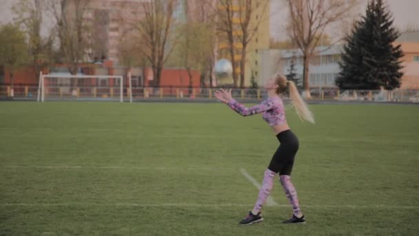 Mladý krásný dívka hrát s míčem na stadionu. — Stock video