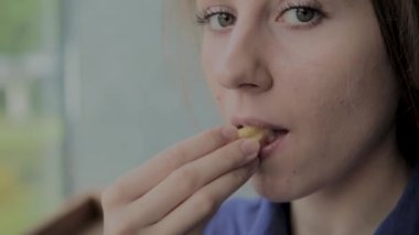 Bir fast-food restoranda kızarmış patates tutan güzel kız