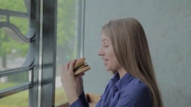 Elinde hamburger tutan güzel bir kız. Fast food restoran.